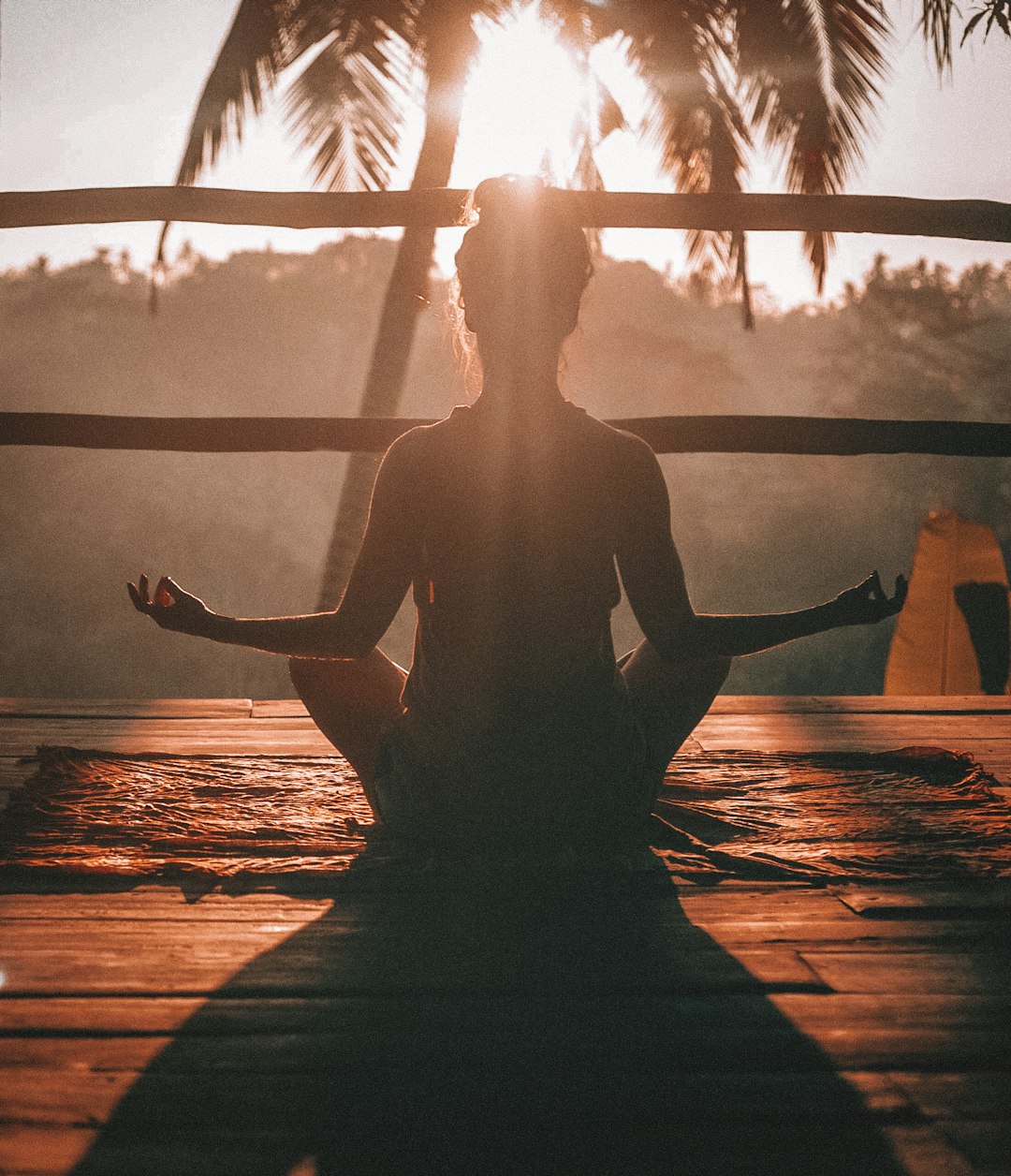 A woman in lotus pose at sunset
